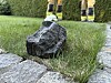 Ein Stein mit ungewöhnlicher Form liegt auf dem Rasen. Im Hintergrund sieht man uniformierte Feuerwehrleute.