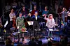 Bühne nach dem Stück, Orchester, vor ihnen die drei Menschen, die sich an den Händen halten