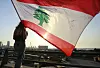 Eine Demonstrantin steht mit einer Flagge Libanons am Jahrestag auf einem Dach in Beirut.