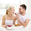 Ein Paar teilt sich Croissants und Erdbeeren.