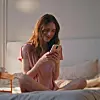 Eine Frau lächelt, während sie auf ihr Handy schaut.