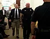 Der Angeklagte wird von einem Polizisten über den Gang geführt