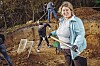 Eine Frau steht mit einer Schippe vor einem Sandhügel