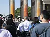 Touristen stehen vor dem Brandenburger Tor, das mit oranger Farbe angesprüht wurde.