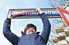 Rachid Messaoudi von den Linken in der Bezirksversammlung Nord streicht symbolisch den Namen Hindenburgstraße auf einem Straßenschild durch.