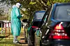 mensch im Schutzanzug an Autos