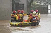 Mitarbeiter der Rettungsdienste bringen Anwohner in Sicherheit, während der Sturm „Babet“ über das Land fegt.
