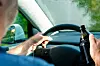 Person fährt Auto unter Konsum von Alkohol.
