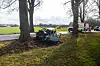 Ein ausgebranntes Auto steht im Straßengraben vor einem Baum