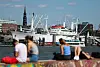 Menschen sitzen am Hafen auf einer Mauer