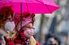Zwei Karnevalisten unter einem pinken Regenschirm.