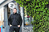 Fabio Haebel steht vor einem efeubewachsenen Lokal mit rundem Logo-Schild in Hamburg.