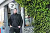Fabio Haebel steht vor einem efeubewachsenen Lokal mit rundem Logo-Schild in Hamburg.