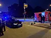 Ein schwarzer Audi steht an einer Ampel. Rechts von dem Auto steht der E-Scooter.