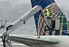 Eine Person steht bei Schneewetter auf einem Kran, an einem Flugzeug.