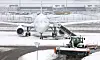 Ein Flugzeug ist komplett eingeschneit am Flughafen.