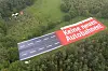 Ein Banner mit der Aufschrift 'Keine neuen Autobahnen!', der einen Autobahnabschnitt darstellt, ist auf einer Landfläche zu sehen.