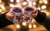 Zwei Frauen stoßen mit Glühwein gefüllten Bechern an.
