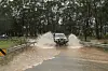 Ein Auto fährt über eine überschwemmte Straße in Vineyard, Sydney.