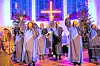 Männer und Frauen des Chores stehen in einer Kirche und singen.