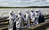 Spargelfrauen in historischen Kostümen gehen beim Start der Spargelsaison in Brandenburg über ein Feld.