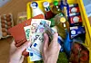 Eine Einkaufskiste mit Lebensmitteln steht auf einem Küchentisch, während eine Frau Euro-Banknoten in den Händen hält.