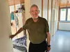 Peter, Jogginghose, olivfarbenes Polo-Shirt, steht im Flur einer Wohnunterkunft von „Fördern & Wohnen“.