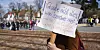 Eine Demonstrantin protestiert mit einem Schild gegen eine Kundgebung der „Querdenken“-Initiative.