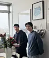 Quang Nguyen und Minh Nguyen lächeln an ihrem Arbeitsplatz neben einem Blumenstrauß.