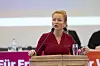 Blonde Frau in roter Bluse an einem Rednerpult