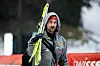 Markus Eisenbichler schaut nach oben und trägt seine Ski.