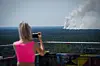 Rauch steigt hinter einer Touristin auf dem Teufelsberg bei dem Brand im Berliner Grunewald auf.