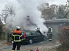 AUs einem Auto steigt Rauch auf. Die Feuerwehr löscht