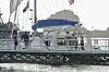 Männer stehen vor und auf einem Segelboot. einer der Männer trägt eine Warnweste