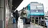 Reisende gehen im Bahnhof Westerland über einen Bahnsteig zu einem wartenden Zug.