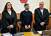 Der Angeklagte (M) steht zu Prozessbeginn zwischen seinen Anwälten im Landgericht.
