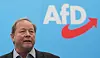 Dirk Nockemann, Landesvorsitzender der AfD Hamburg steht vor einem bauen Hintergrund mit AfD Logo