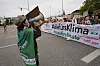 Ein Demonstrant hält ein Megaphon vor dem Mund und spricht zu den Teilnehmern hinter dem Banner 'alle fürs Klima'