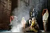 Schauspieler stehen vor einer skurril-fantastischen Waldkulisse.