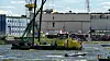An einem Ponton auf der Elbe baumelt eine kopflose Puppe am Kran.