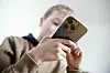 Ein Kind im braunen Pullover schaut auf ein Handy.