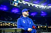 Steffen Baumgart lehnt mit Sky-Mikro auf einem Tisch am Spielfeldrand