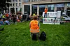 Ein Demonstrant gegen die Corona-Politik der Regierung mit einer Warnweste 'Wir sind die 99 Prozent' sitzt auf einer Wiese am Leipziger Platz und hört einem Vertreter der Partei Die Basis zu.