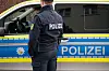 Ein Polizist steht vor einem Einsatzfahrzeug.