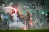 Pyrotechnik und maskierte Fans auf dem Spielfeld.