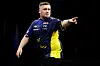 Darts-Profi Luke Littler zeigt zufrieden in den Raum