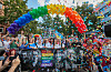 Menschen feiern beim CSD in Hamburg unter einem Regenbogenbogen aus Luftballons und Konfetti.