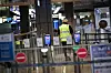 Eine Flughafenmitarbeiterin geht durch die geschlossene und menschenleere Sicherheitskontrolle im Flughafen Hamburg.