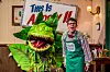 Im Inneren des Blumenladens, links eine riesige grüne, gefährlich wirkende Pflanze, rechts Florist Seymour
