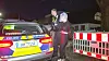 Frau wird mit Spuckhaube zum Streifenwagen geführt
